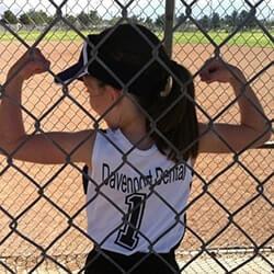 Little girl in softball uniform flexing illustrating this dentist in Tucson's involvement in the community